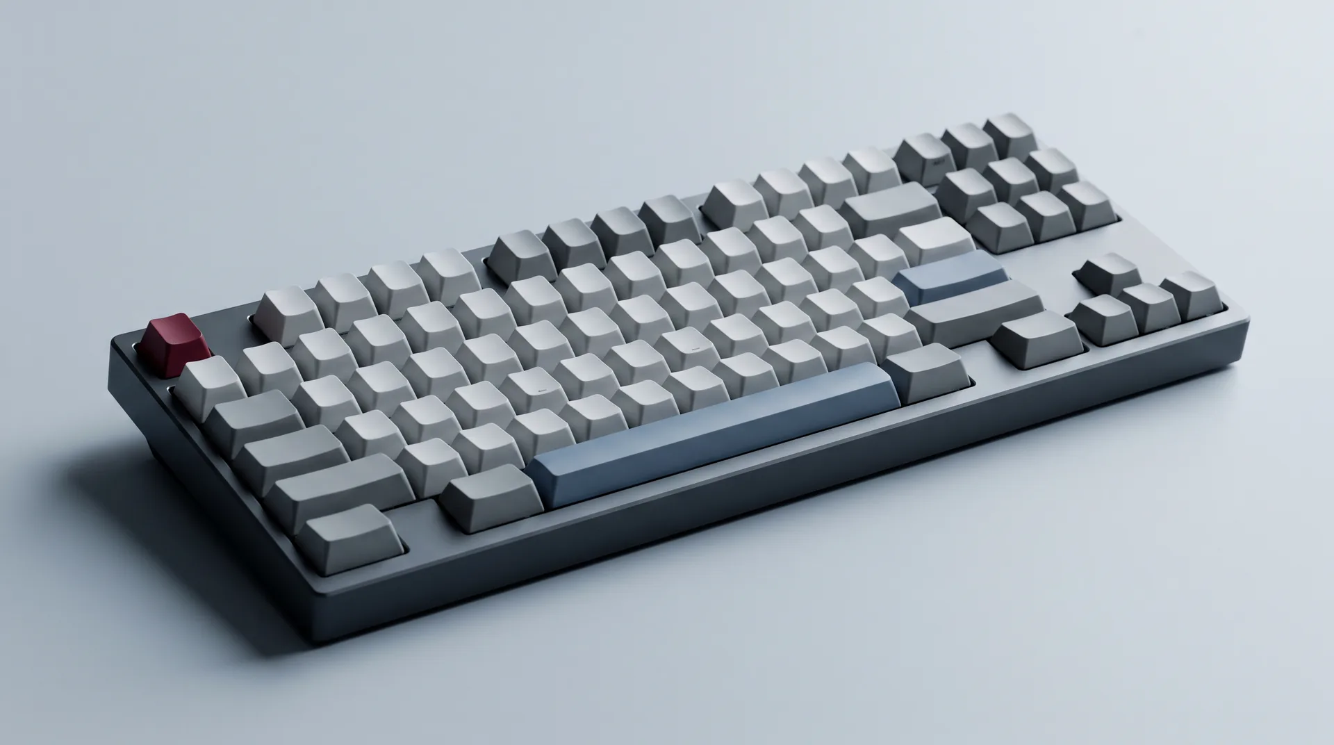A tenkeyless mechanical keyboard with grey and slate-blue keycaps and a single deep red escape key.