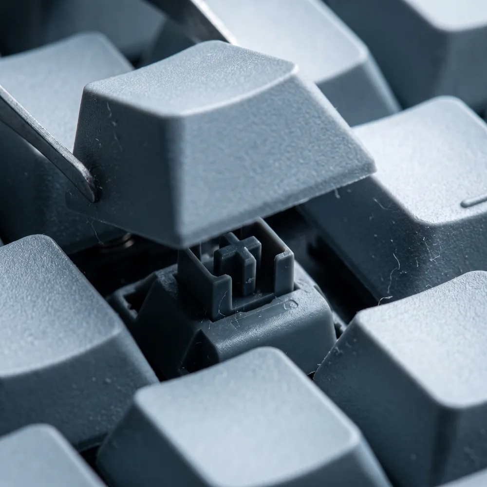 A keycap lifted from the board to reveal the cross-shaped switch stem beneath.